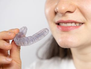 Woman holding occlusal splint for TMJ disorder